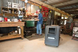 man using a Portacool evaporative cooler in his home workshop to stay cool